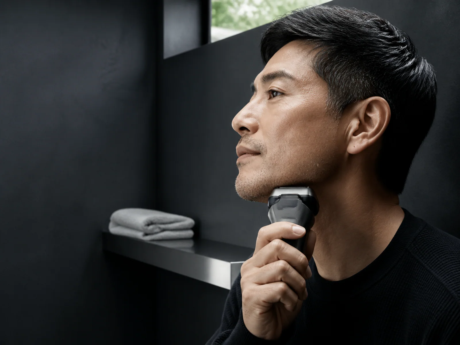 顎へ電気シェーバーを当てる男性の横顔