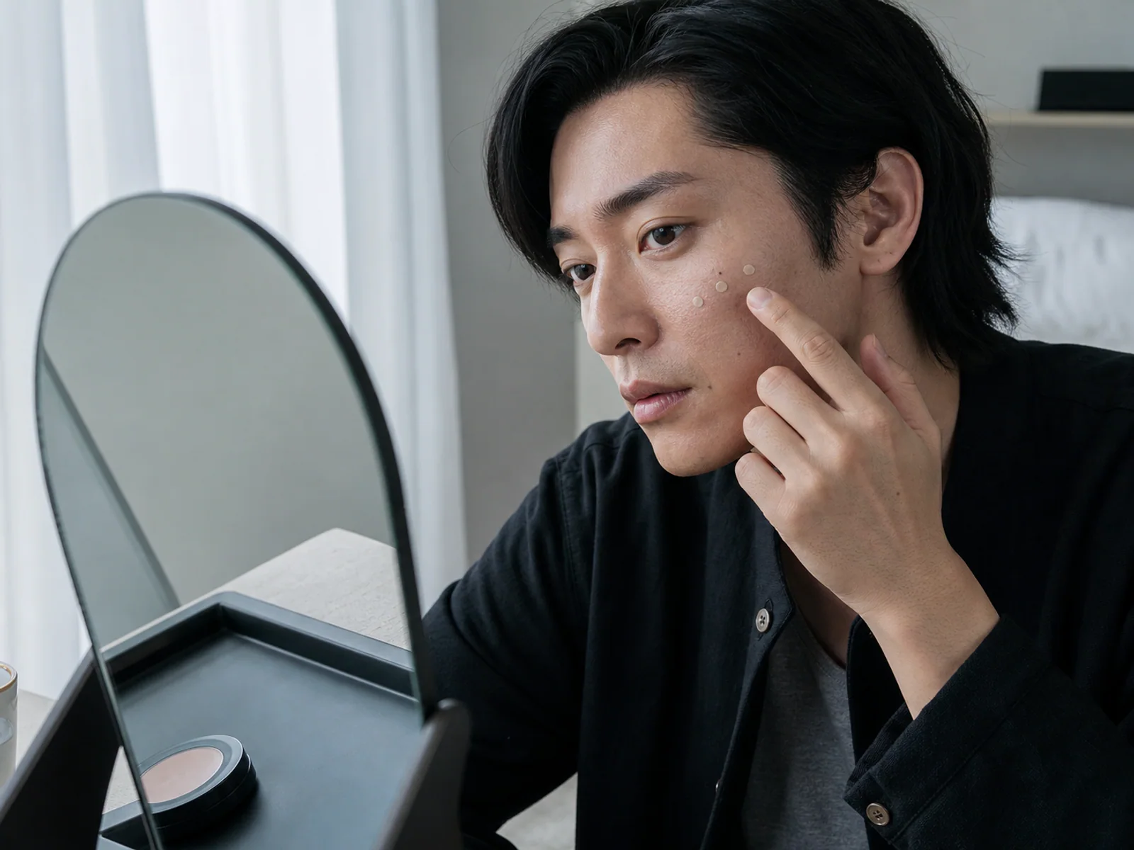 薄いベースを頬へ少量ずつ置く男性