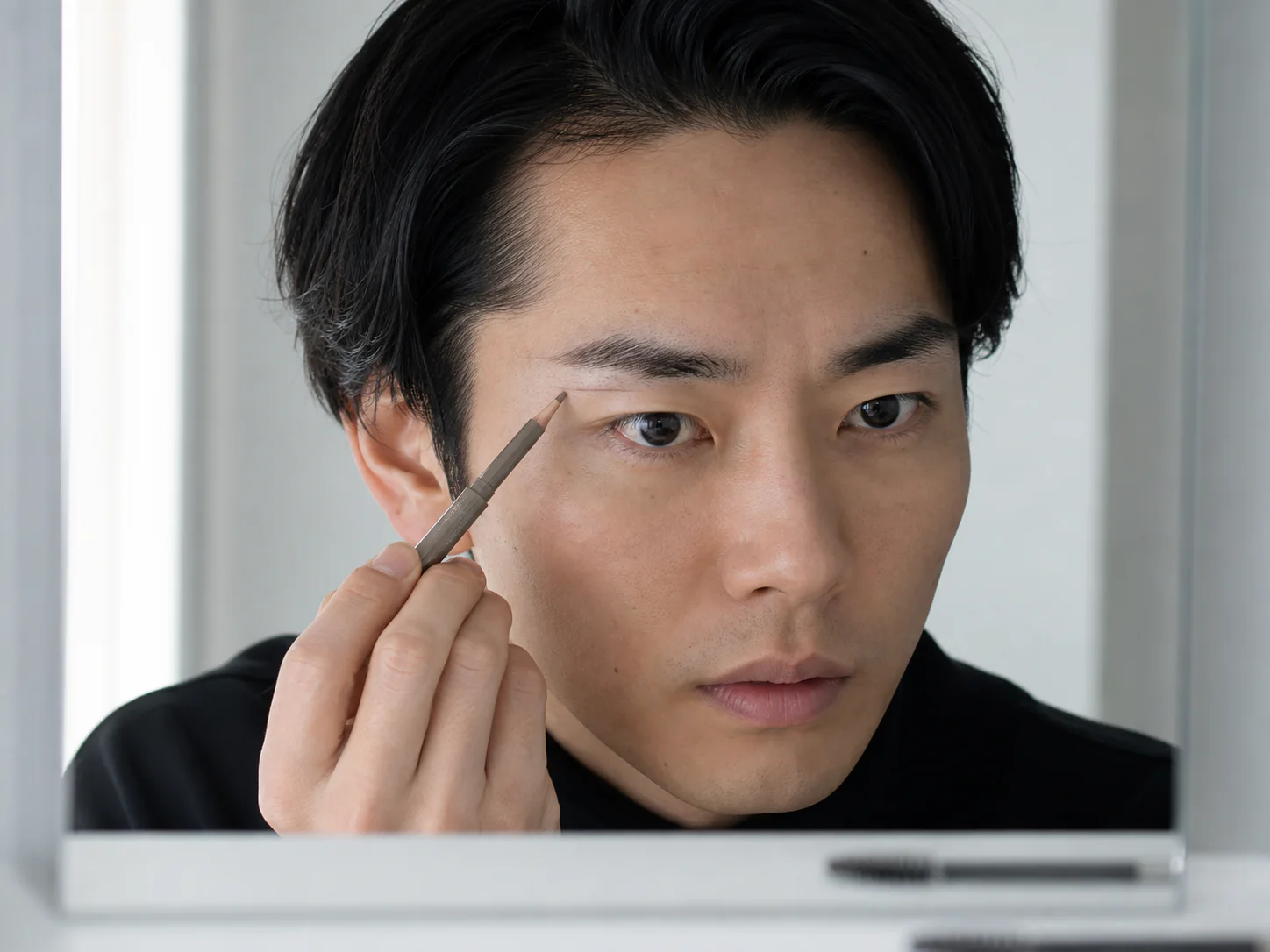 左右差を確認しながら眉の輪郭を整える男性