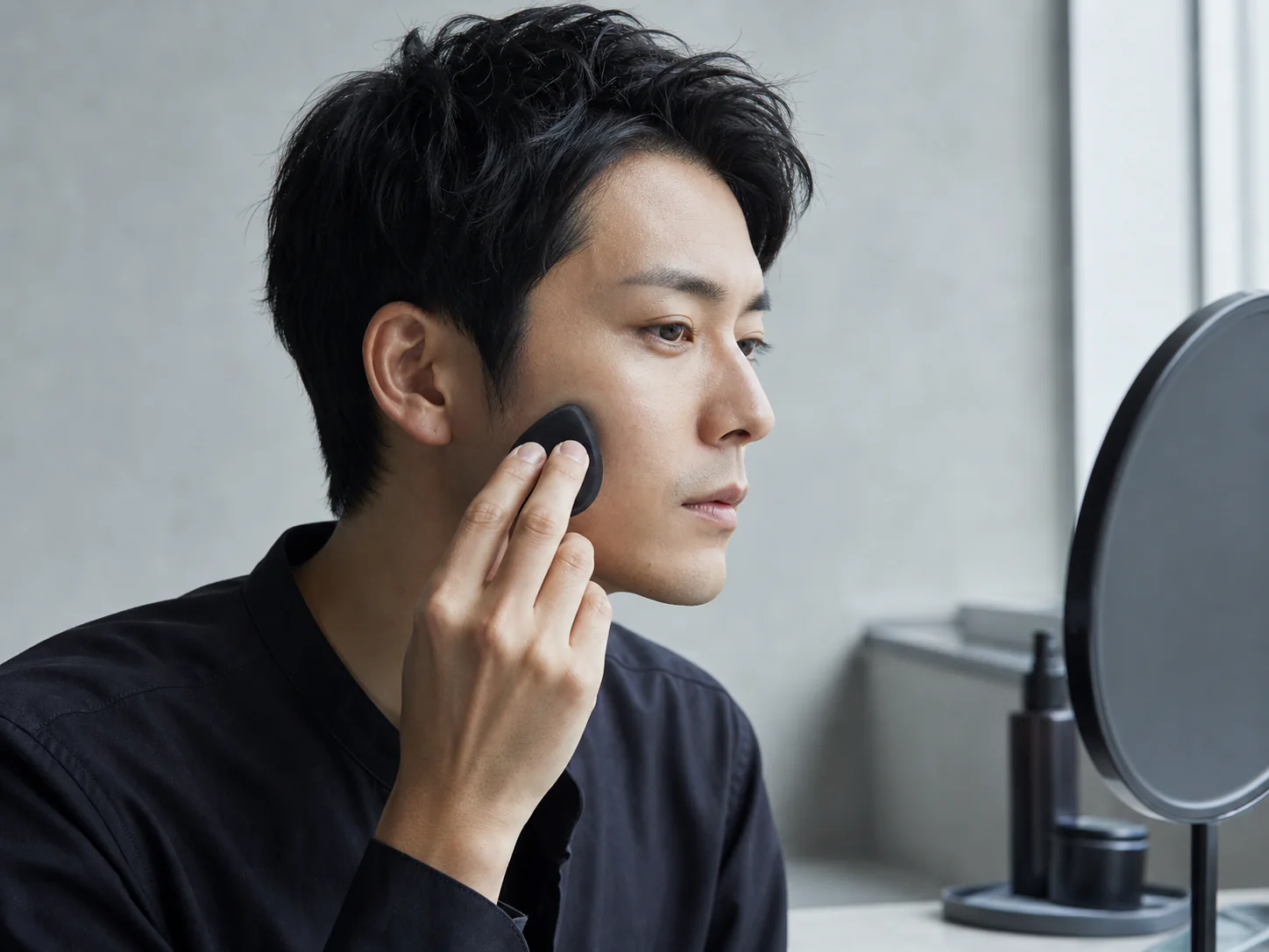 スポンジで薄くベースをなじませる男性